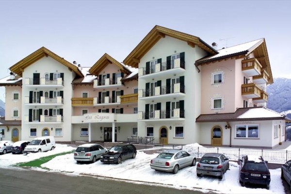 Budynek hotelu z parkingiem w zaśnieżonym zimowym krajobrazie w tle.