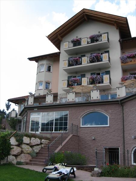 Budynek hotelu z balkonami ozdobionymi kwiatami.