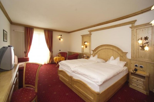 Pokój hotelowy z łóżkiem małżeńskim i drewnianymi meblami.