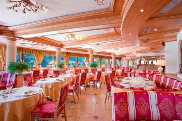 Elegancka restauracja z czerwonymi i złotymi detalami oraz dużymi oknami.