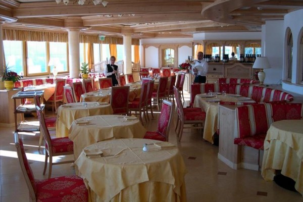 Restauracja z drewnianym wnętrzem, czerwonymi krzesłami i żółtymi obrusami.