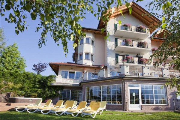 Budynek hotelu z balkonami ozdobionymi kwiatami i leżakami w ogrodzie.