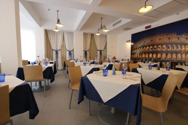 Elegancka restauracja z niebiesko-białymi obrusami i dużym obrazem Koloseum na ścianie.