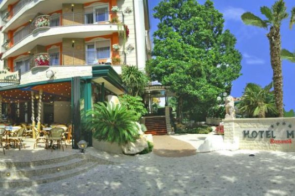 Wejście do hotelu z zewnętrznymi miejscami do siedzenia i palmami.