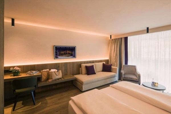 Nowoczesny pokój hotelowy z podwójnym łóżkiem, sofą i biurkiem.