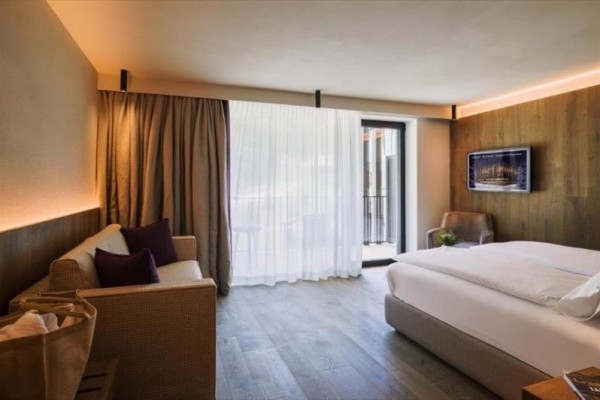 Nowoczesny pokój hotelowy z dużym łóżkiem, sofą i balkonem.