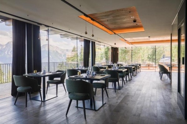 Nowoczesna restauracja z widokiem na góry przez duże okna.