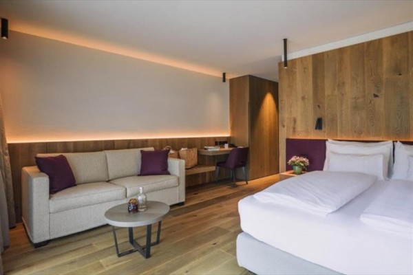 Nowoczesny pokój hotelowy z drewnianymi elementami, łóżkiem i sofą.