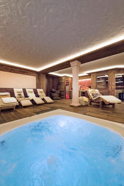 Pomieszczenie wellness z jacuzzi i leżakami.