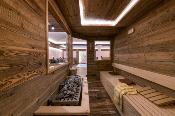 Sauna z drewnianym wnętrzem, ławkami i kamieniami grzewczymi.