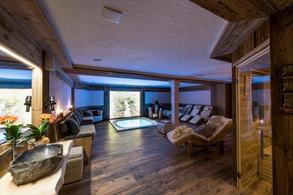 Luksusowe pomieszczenie spa z jacuzzi, leżakami i drewnianą boazerią.