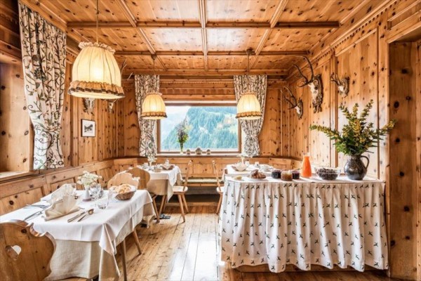 Drewniana górska restauracja z oknem z widokiem na góry i dekoracjami z trofeami na ścianach.