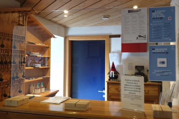 Recepcja z drewnianym pulpitem, kluczami na ścianie i ulotkami informacyjnymi.