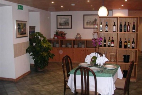 Elegancko nakryty stół w restauracji z drewnianą boazerią i regałem z butelkami wina.