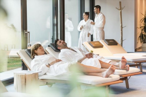 Ludzie w szlafrokach odpoczywają na leżakach w środowisku spa.