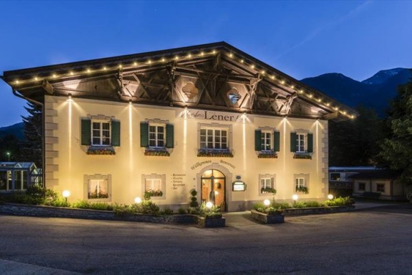 Oświetlony budynek stylowego hotelu z oknami z okiennicami w górskiej scenerii o zmierzchu.