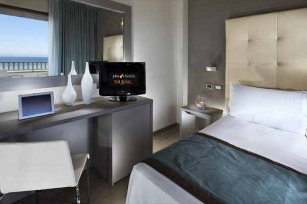 Nowoczesny pokój hotelowy z widokiem na morze, biurkiem, telewizorem i łóżkiem.