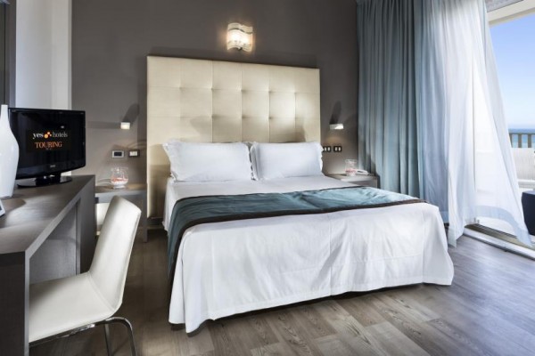 Nowoczesny pokój hotelowy z łóżkiem małżeńskim i widokiem na morze.
