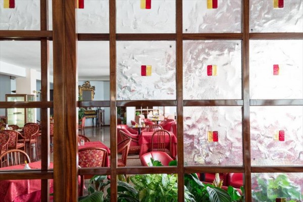 Restauracja oddzielona drewnianą ścianą ze szklanymi panelami i czerwonymi obrusami.