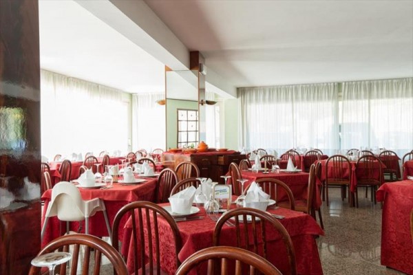 Restauracja ze stolikami pokrytymi czerwonymi obrusami i drewnianymi krzesłami.