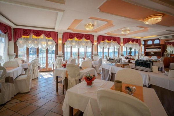 Elegancko nakryta restauracja z białymi obrusami i czerwonymi zasłonami.