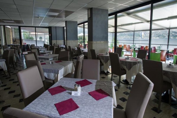 Restauracja z szarymi obrusami i czerwonymi serwetkami na stołach z widokiem na jezioro.