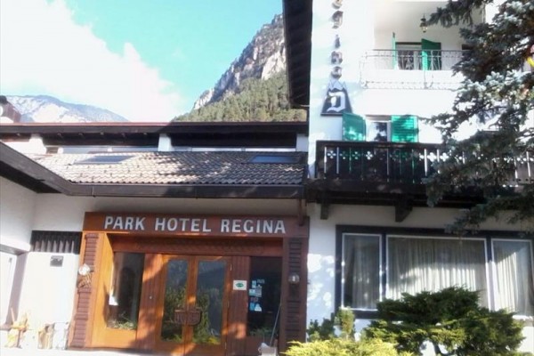 Wejście do hotelu Park Hotel Regina z górami w tle.