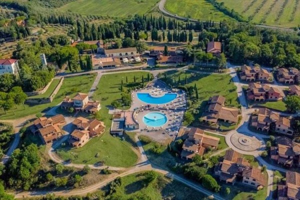 Ośrodek z basenami otoczony zielenią i domkami z lotu ptaka.