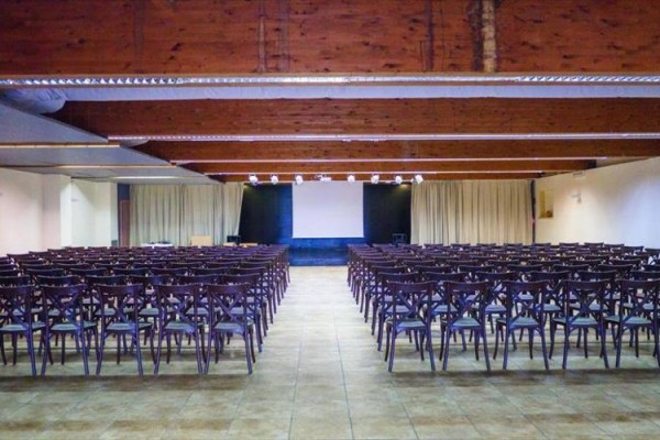 Pusta sala konferencyjna z krzesłami i ekranem projekcyjnym.