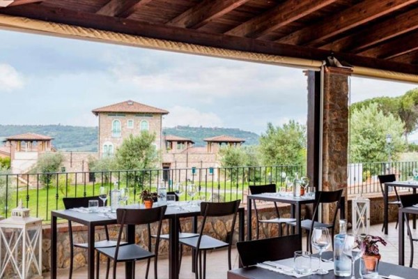 Restauracja z zewnętrznymi miejscami do siedzenia z widokiem na krajobraz z domami.