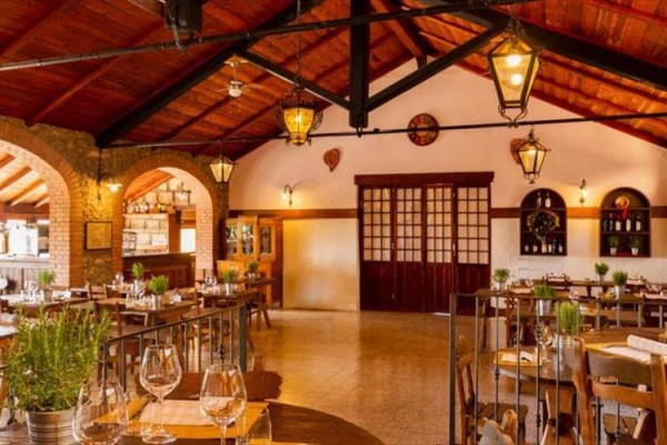Wnętrze rustykalnej restauracji z drewnianymi belkami i nakrytymi stołami.