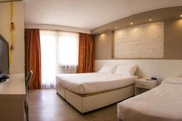 Pokój hotelowy z łóżkiem małżeńskim, łóżkiem pojedynczym i telewizorem.