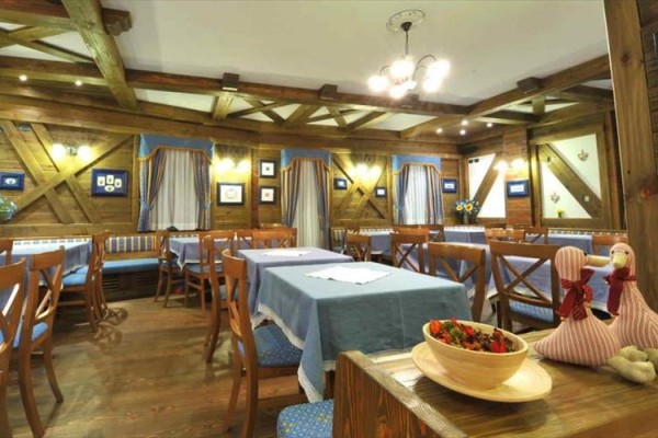 Restauracja z drewnianym wnętrzem i niebieskimi obrusami na stołach.