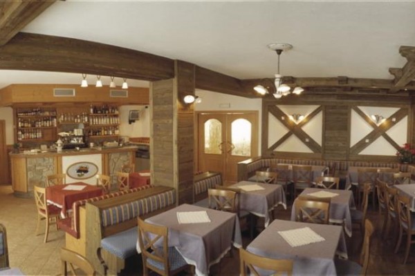Wnętrze restauracji z drewnianymi meblami i barem w tle.