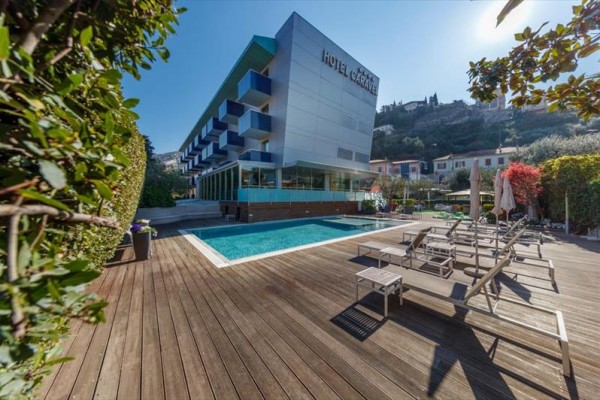 Nowoczesny hotel z basenem zewnętrznym i tarasem otoczonym leżakami.