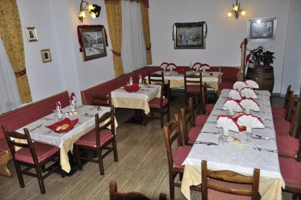 Restauracja z przygotowanymi stołami, czerwonym obiciem i żółtymi obrusami.