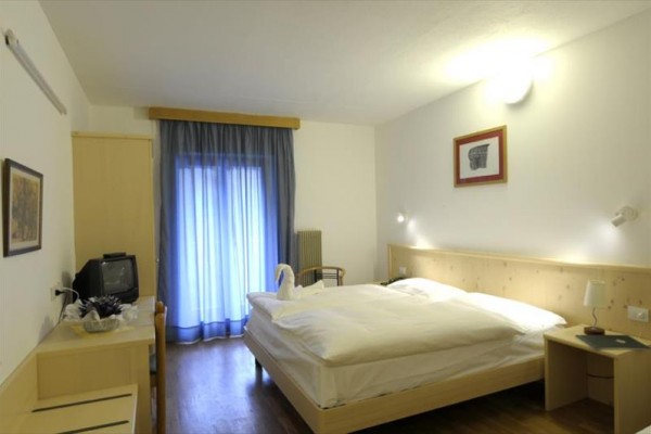 Pokój hotelowy z łóżkiem małżeńskim i balkonem z niebieskimi zasłonami.
