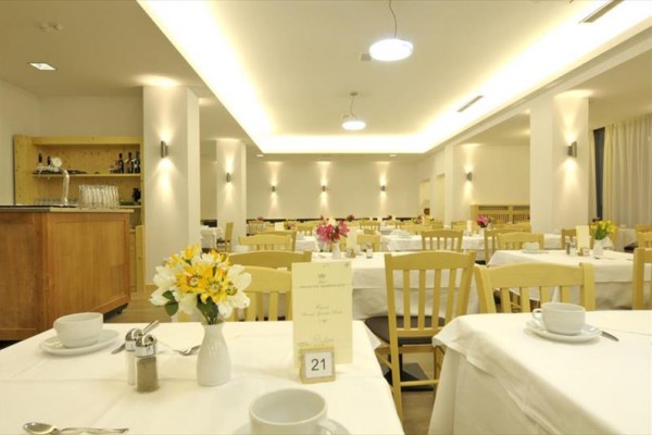 Elegancka restauracja z drewnianymi krzesłami i obrusami, z kwiatami na stołach.