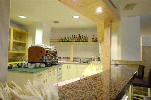 Nowoczesny bar z ekspresem do kawy i butelkami alkoholu na półkach.