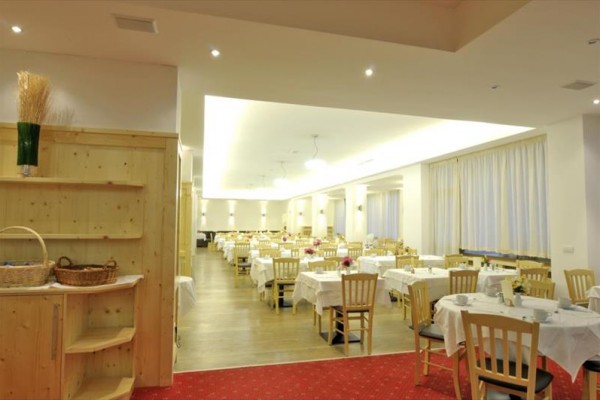 Jasna restauracja z nakrytymi stołami i drewnianymi krzesłami.