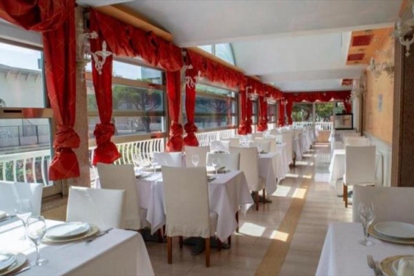 Elegancka restauracja z białymi obrusami i czerwonymi zasłonami.