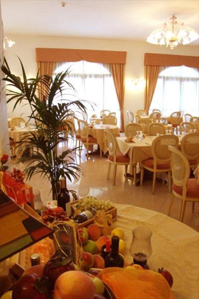 Stylowa jadalnia z eleganckimi stołami, jasnymi meblami i owocami na pierwszym planie.