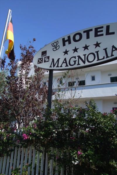 Znak hotelu Magnolia przed białym budynkiem z niemiecką flagą w tle.