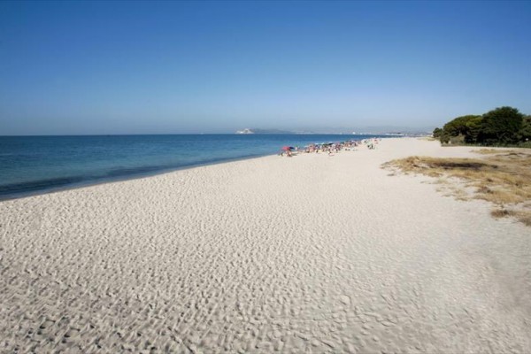 Długa piaszczysta plaża z ludźmi nad morzem i niebieskim niebem.