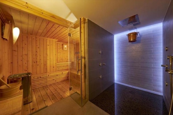 Sauna z drewnianymi ławkami obok nowoczesnego prysznica.