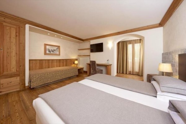 Nowocześnie urządzony pokój hotelowy z łóżkiem małżeńskim, sofą i biurkiem.  