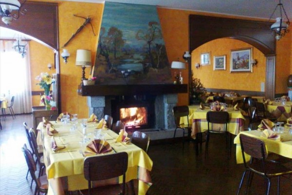 Restauracja z kominkiem i nakrytymi żółtymi stołami.  