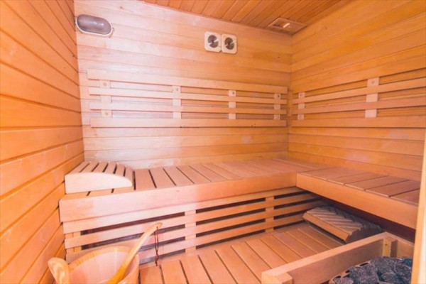 Drewniana sauna z ławkami i wiadrami na wodę.