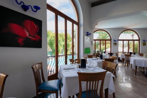 Wnętrze restauracji ze stołami nakrytymi na obiad z widokiem na zewnętrzną zieleń.
