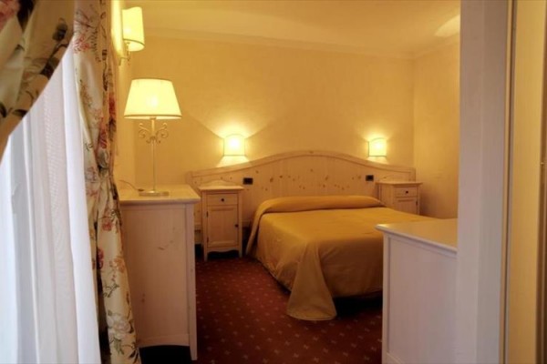 Pokój hotelowy z łóżkiem małżeńskim, dwoma lampami i beżowym wystrojem.